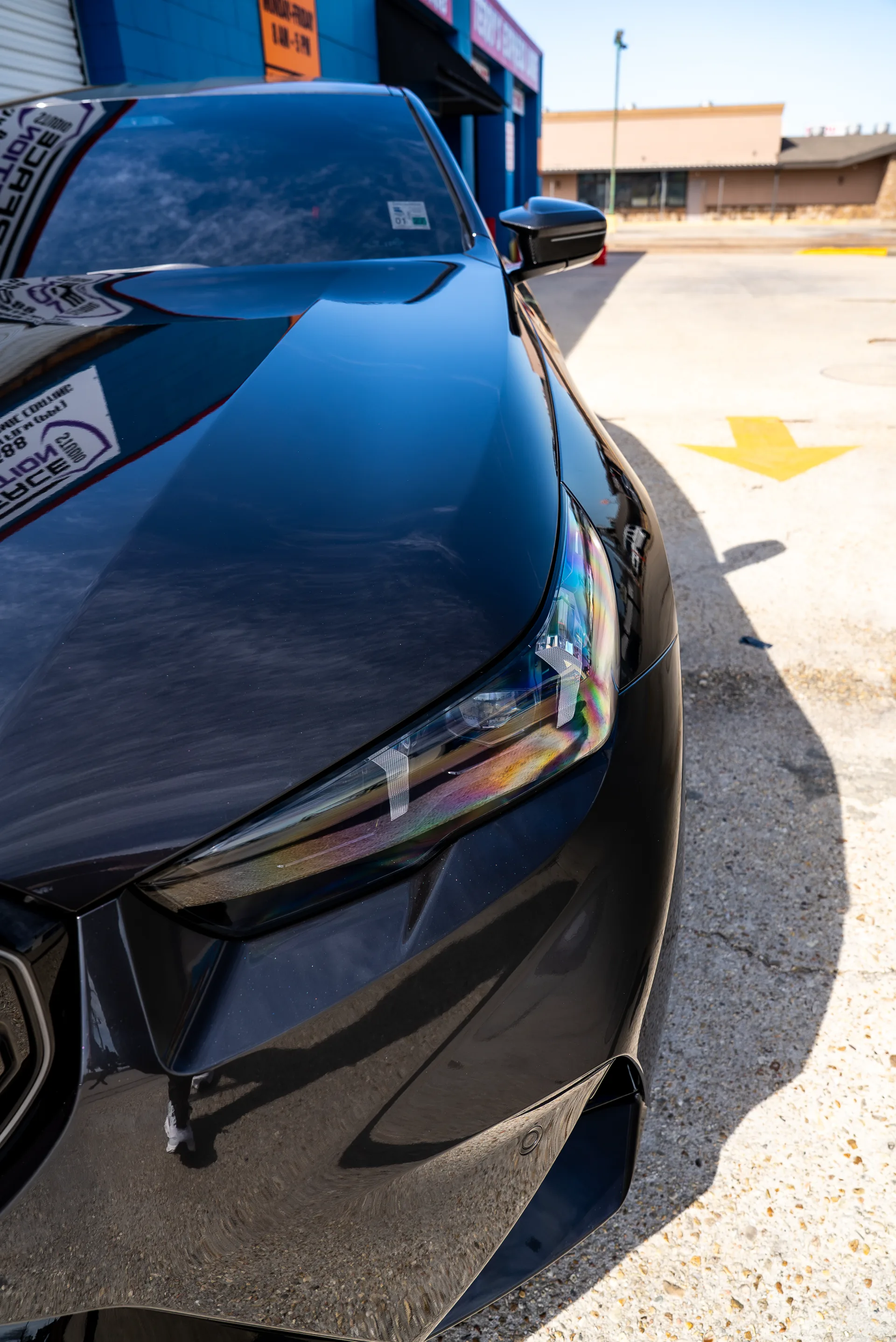Paint flare reflecting off the headlight of a ceramic-coated BMW M5