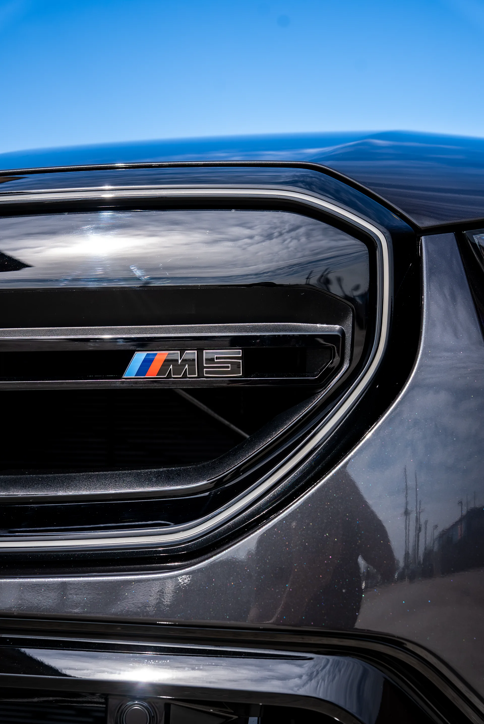 Fender vent badge of a BMW M5 against a clear sky