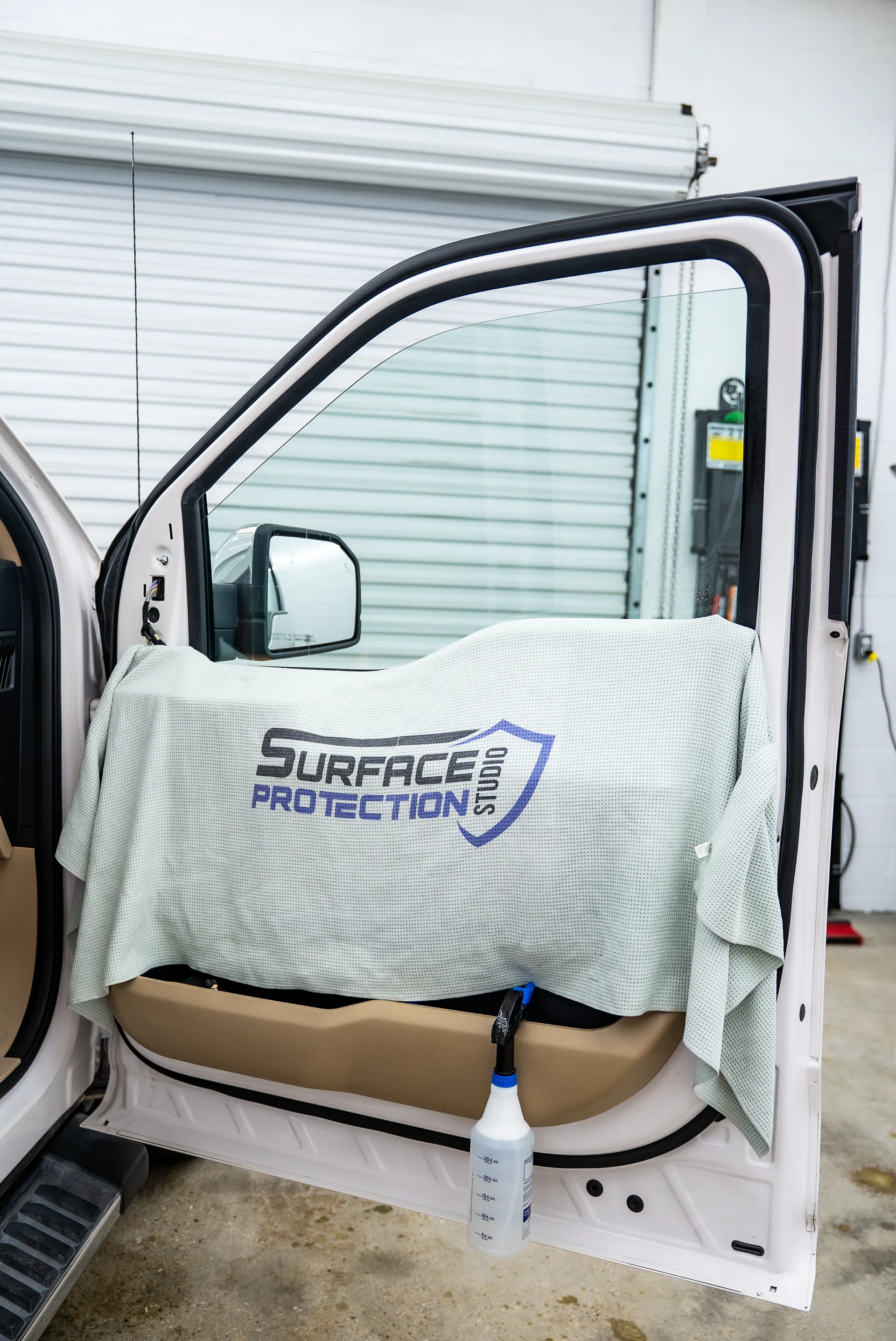 Surface Protection Studio shop door with a branded towel hanging beside it