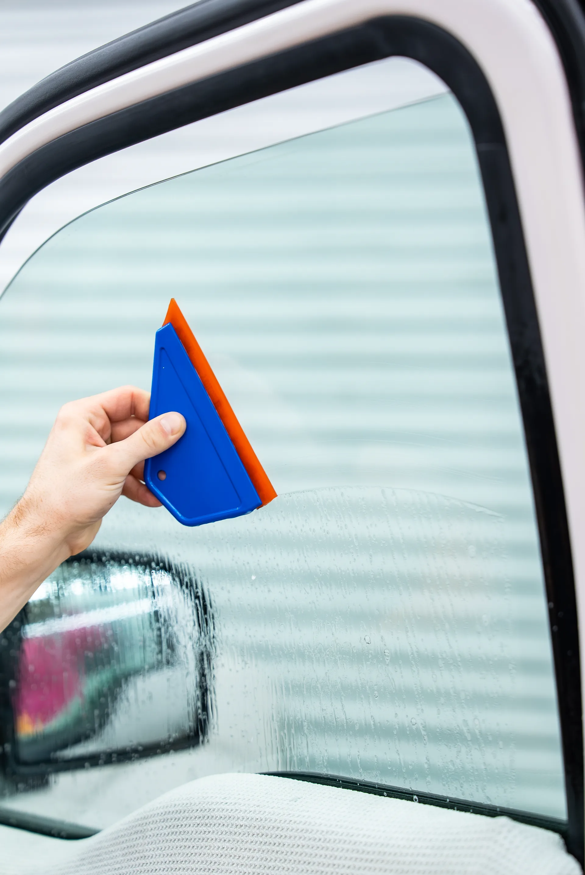 Squeegee working film onto glass during a ceramic tint installation