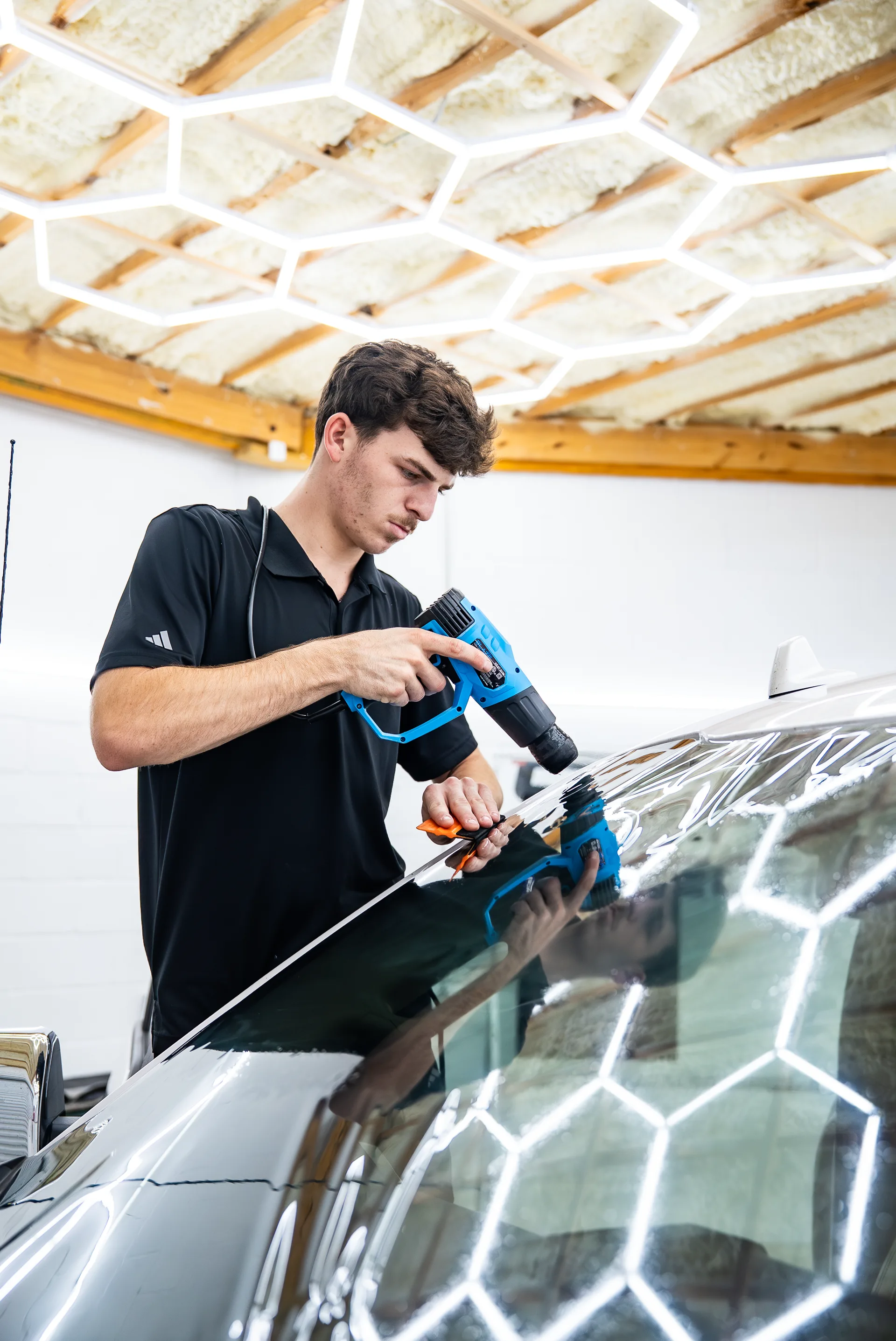 Technician using a heat gun to shrink window film on a truck hood