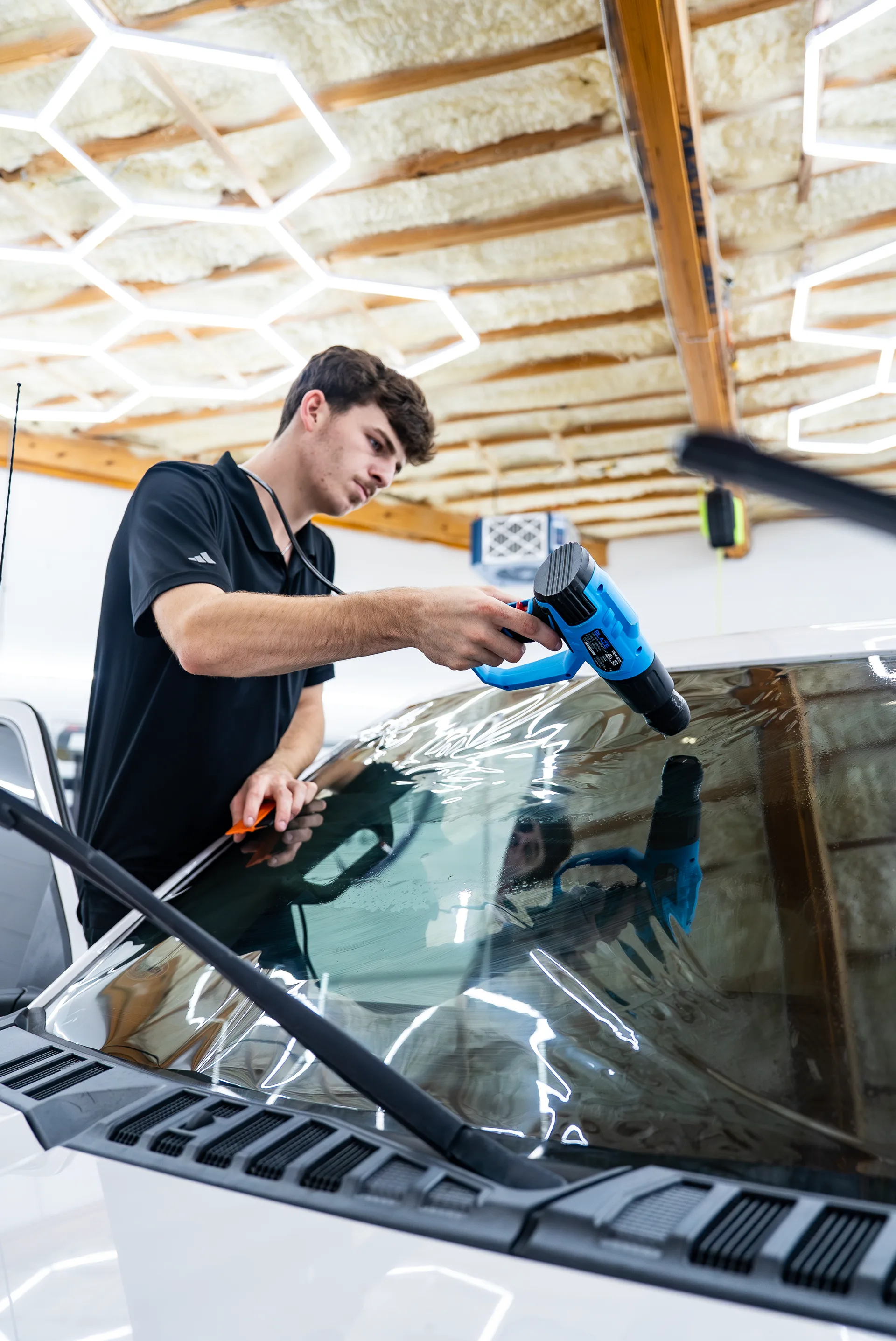 Owner heat-shrinking window tint on a windshield at Surface Protection Studio