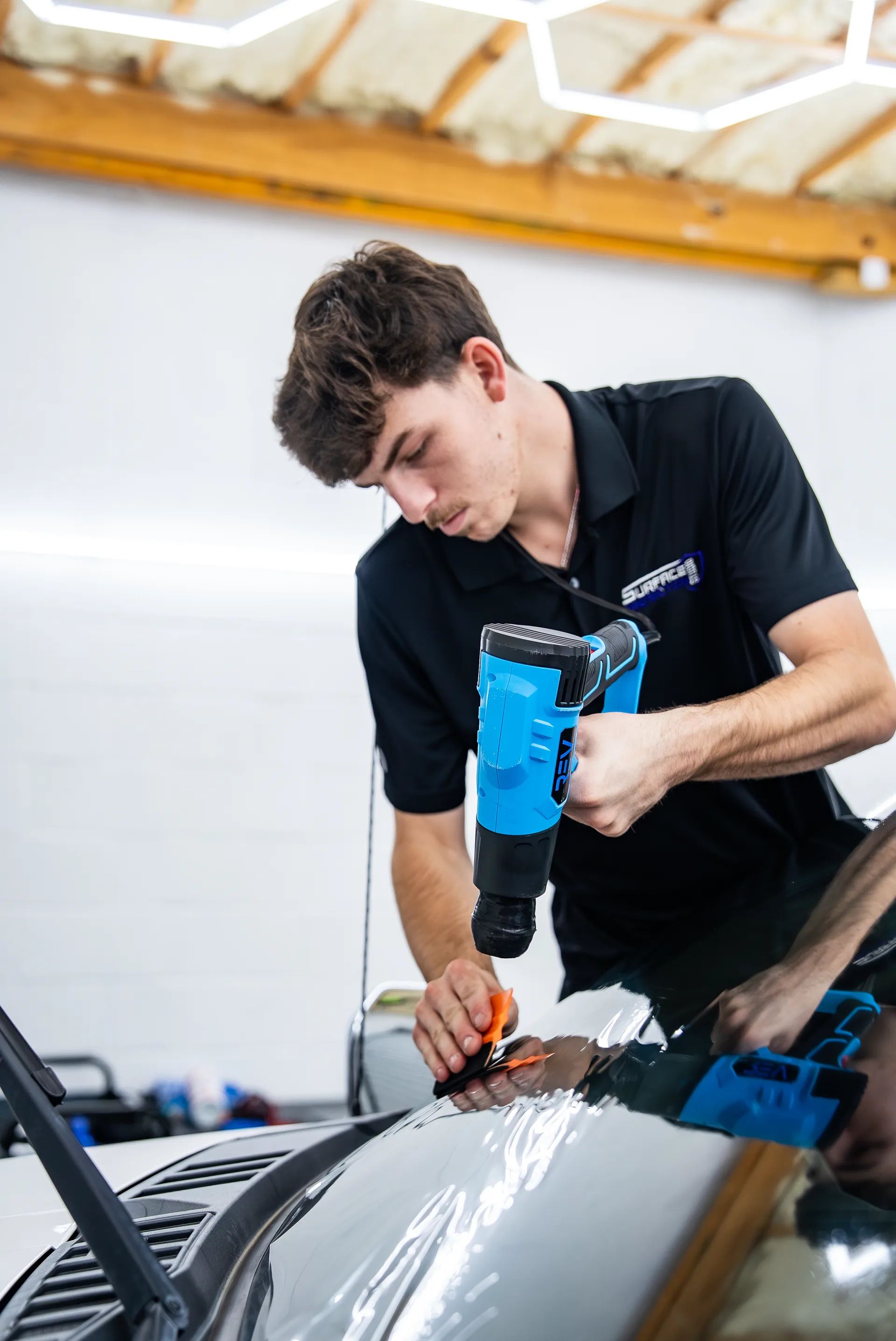 Technician in a Surface Protection Studio polo using a shrink tool during an install